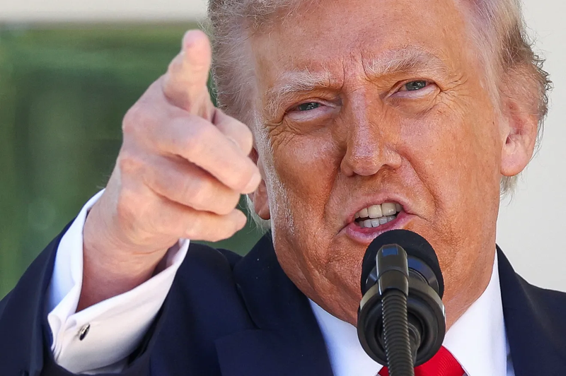 President Donald Trump speaks into a microphone and points while delivering remarks at the White House