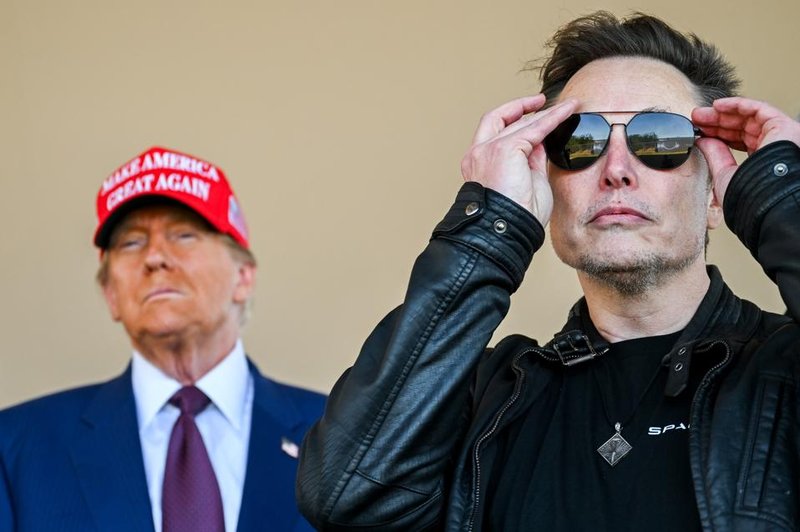 Elon Musk adjusts his sunglasses while Donald Trump, wearing a red "Make America Great Again" hat, stands in the background.