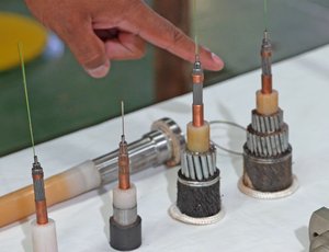 A hand points at metal mechnical parts on a table.