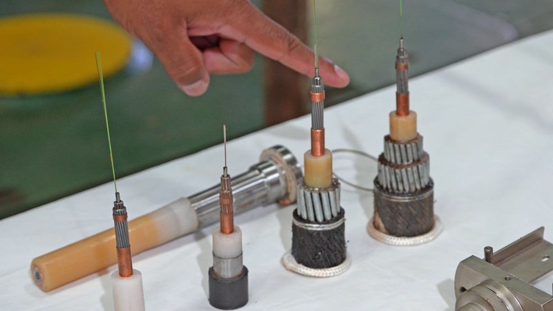 A hand points at metal mechnical parts on a table.