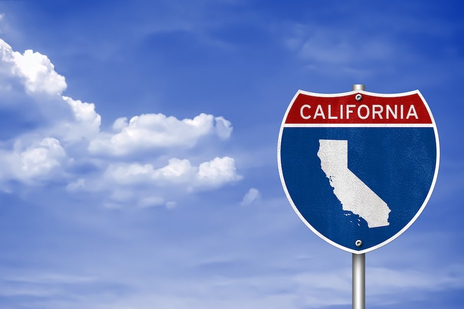 An image of blue sky and a blue highway sign that says "California," with a white image of the state map