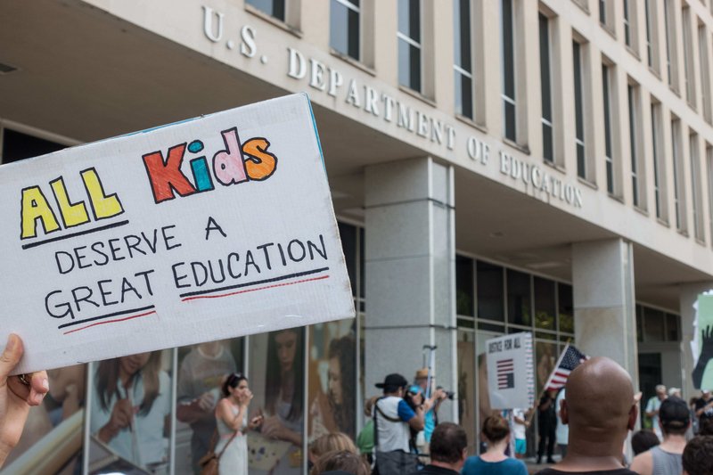 A protest in front go the U.S. Department of Education and a sign reading" All Kids Deserve a Great Education"