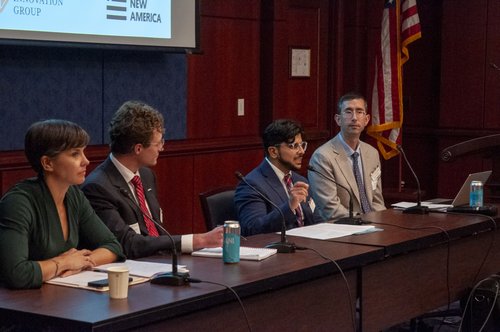 three panelists and one moderator at a long table with microphones