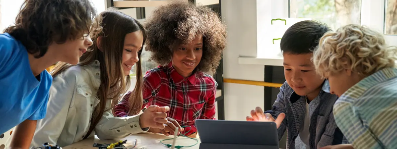 A group of children gather around an Ipad in class.