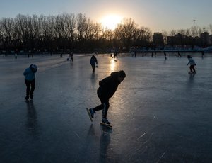 People skate together on a lake in a local park.
