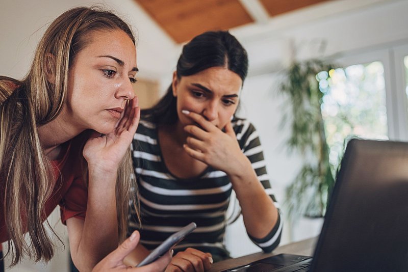 Two young woman experiencing online fraud and trying to solve it