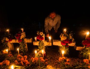 A woman lights candles on graves during 'Day of the Dead' celebrations