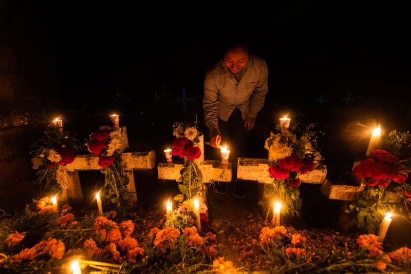 A woman lights candles on graves during 'Day of the Dead' celebrations