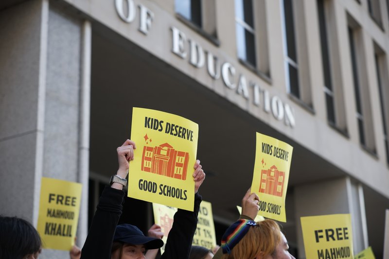 Protest being held outside the Department of Education with individuals holding signs that read "kids deserve good schools."