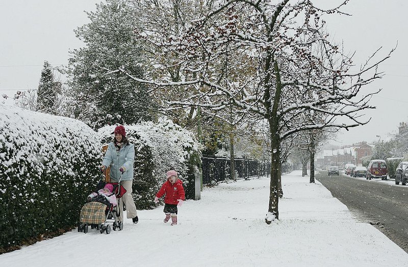 Families walks in a neighborhood and enjoys the winter weather and snow fall.