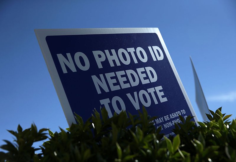 A "No Photo ID Needed To Vote" sign is seen outside a county government center for early voting.