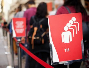 A queue with red signs indicating a one-hour wait time.
