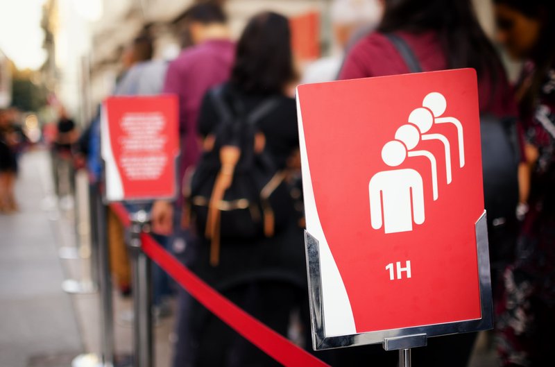 A queue with red signs indicating a one-hour wait time.