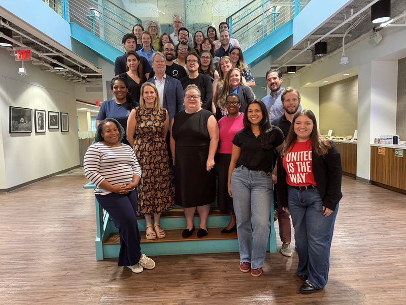Over 30 people pose for a picture on the staircase in New America's office.