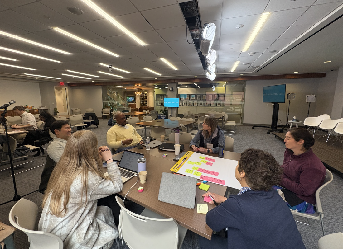 Educators, designers, and developers seated at a table discussing an ed tech tool