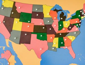 A U.S. map on a bulletin board with each state a different color, and push pins showing the  location of the capital of each state.