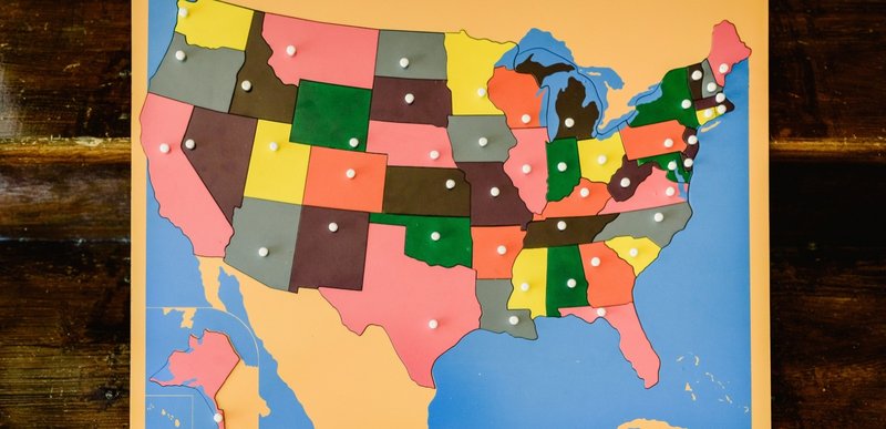 A U.S. map on a bulletin board with each state a different color, and push pins showing the  location of the capital of each state.
