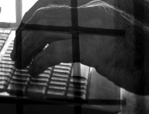 Man typing on computer with an overlay of prison bars.