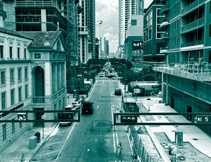 A view of a city street lined with multistory buildings and construction scaffolding, in teal.