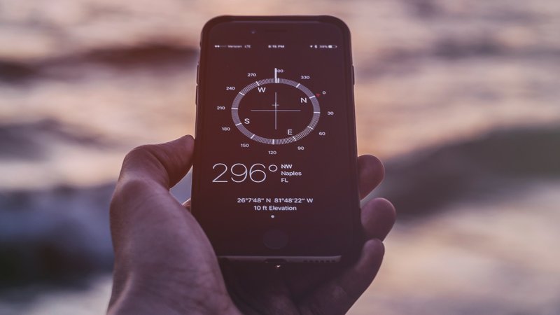 A hand holds a phone with a digital compass.