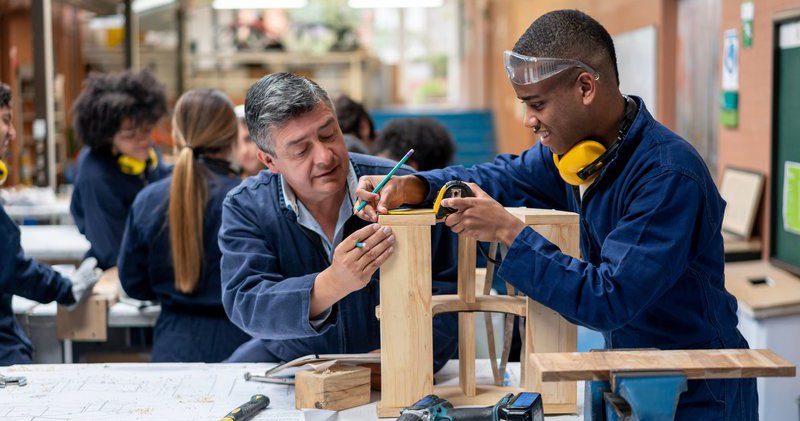 A young apprentice receives carpentry training from a classroom instructor.