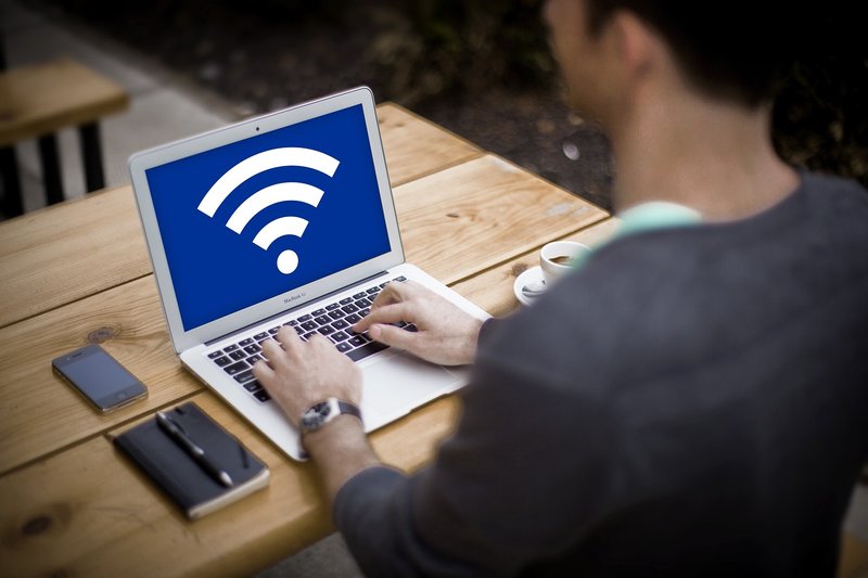 Person typing on their laptop that displays WiFI symbol