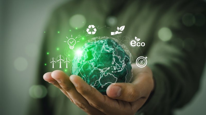 A hand holds a green earth with tech symbols swirling around it.