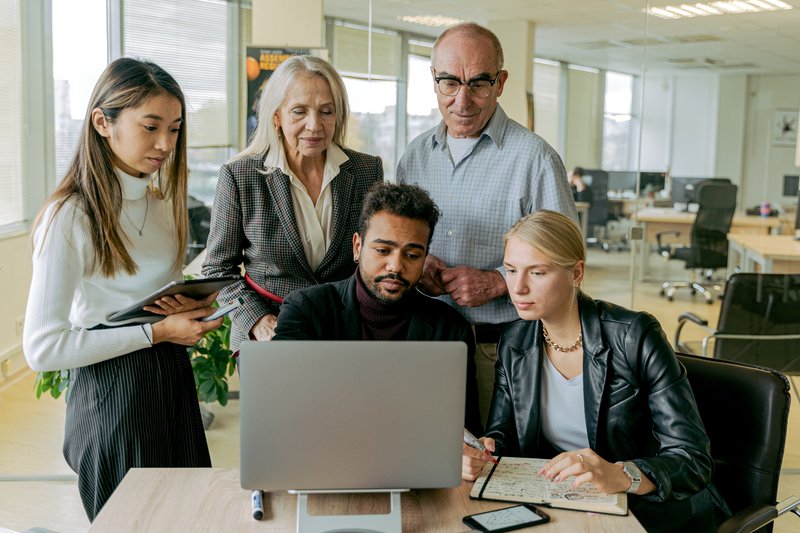 People of different race, gender, and age gathered seriously around a laptop