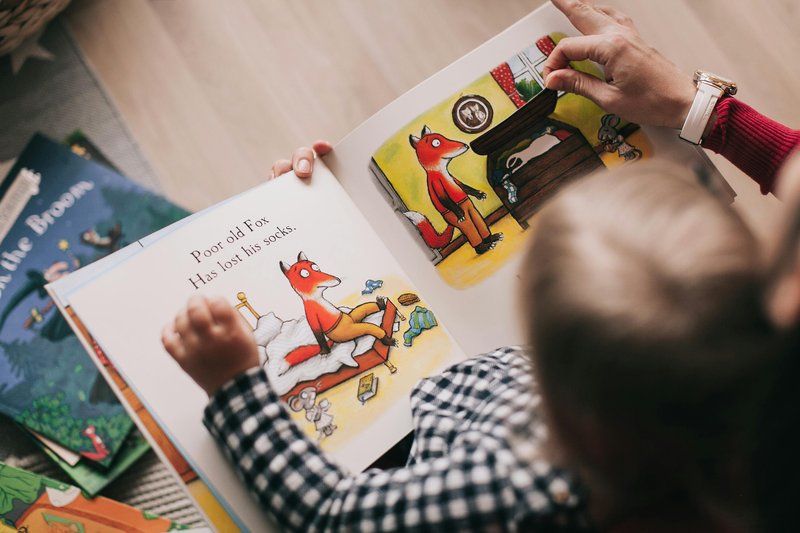 Child reading an illustrated book with an adult