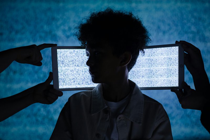 A child in front of a screen held up by four hands.
