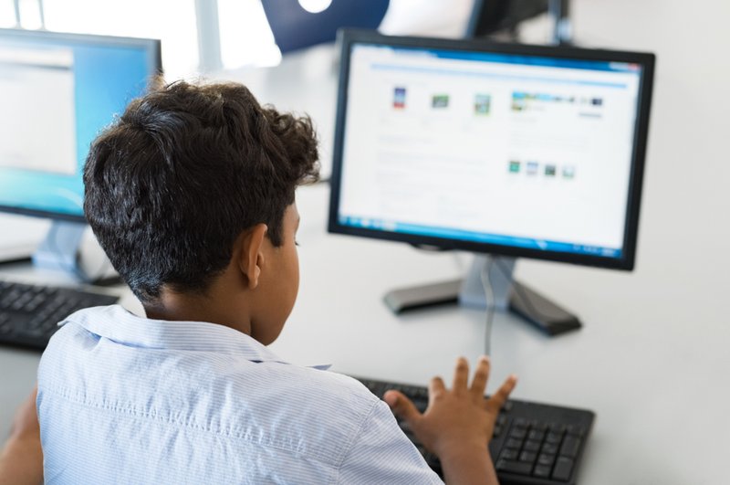A ten year old boy typing on a school computer.