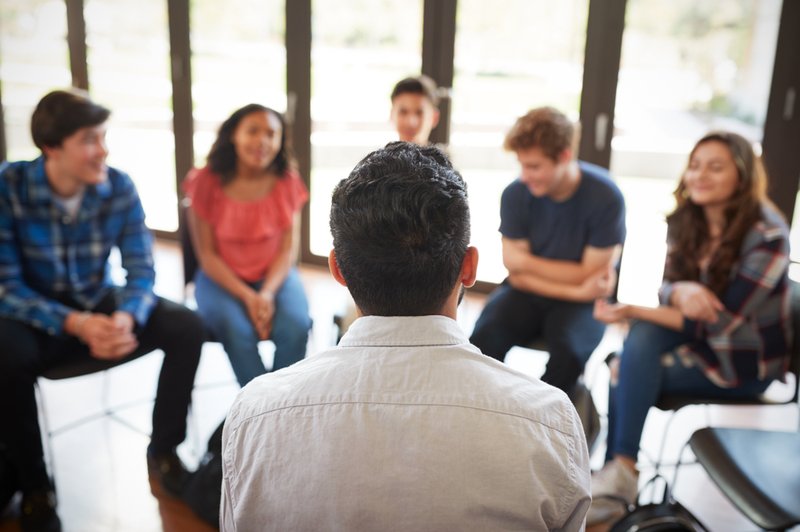 Rear View Of Male Leading Focus Group Amongst High School Pupils.