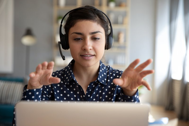 A woman on a video call on her laptop wearing headset