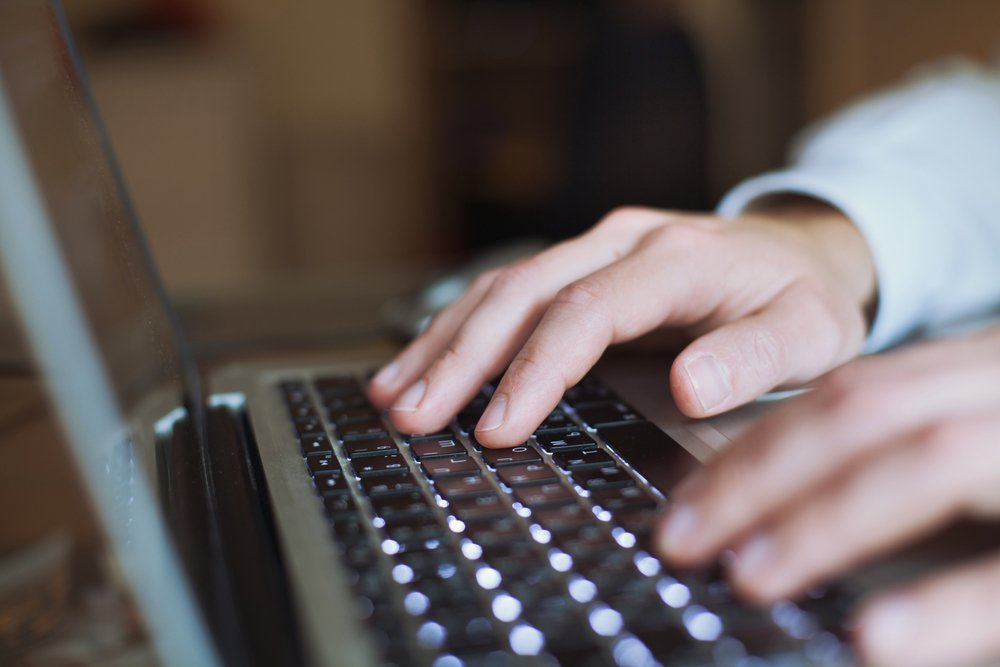 Two hands typing on a laptop keyboard