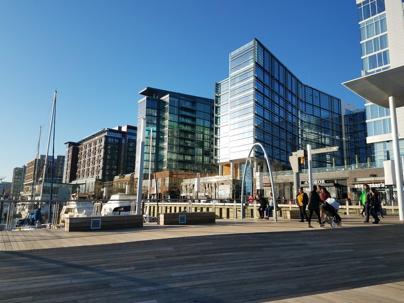 Boats are docked below shiny glass and brick buildings at the Wharf in southeast DC.