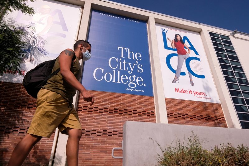 A man walks past a building with large banners reading "The City's College" and "LACC" with "Made in LA."