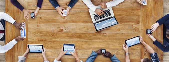 Group of people at a table using digital devices