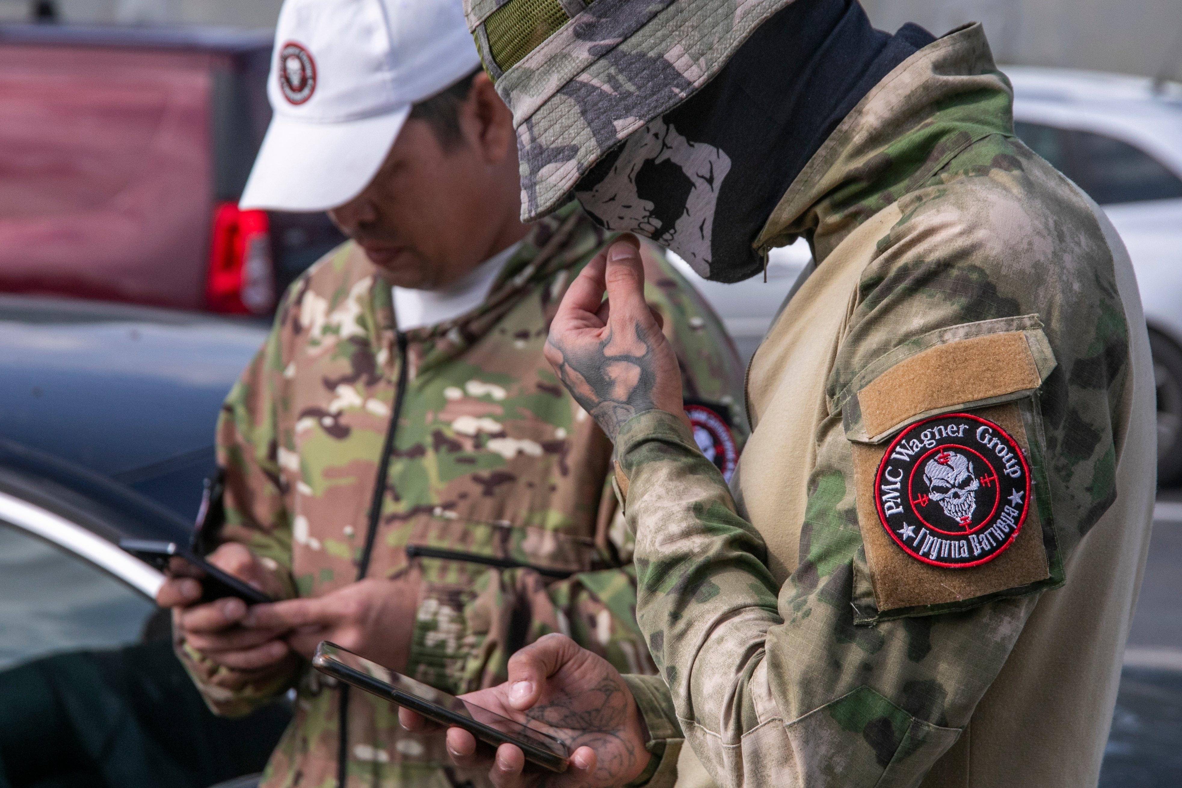 Wagner group soldiers in camo gear on their phones.