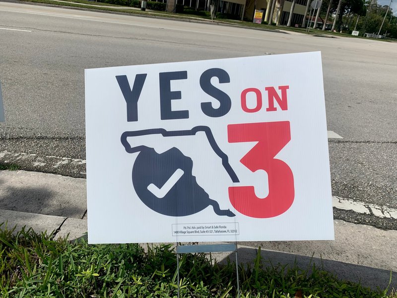 Sign reading "YES ON 3" with an outline of Florida and a checkmark, set by a roadside.